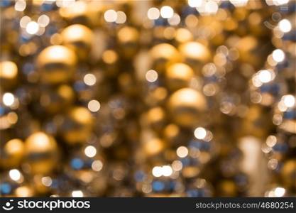 holidays, luxury and background concept - blurred golden christmas decoration or garland of beads or balls bokeh