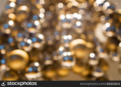 holidays, luxury and background concept - blurred golden christmas decoration or garland of beads or balls bokeh