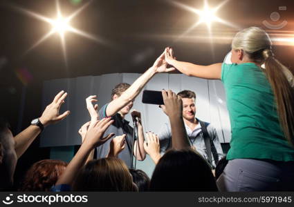 holidays, music, gesture, nightlife and people concept - close up of woman fan making high five with singer at concert in night club