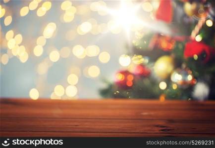 holidays, new year and celebration concept - close up of empty wooden surface or table over christmas tree and lights background. empty wooden surface over christmas tree lights