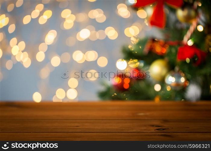 holidays, new year and celebration concept - close up of empty wooden surface or table over christmas tree and lights background