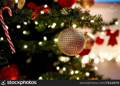 holidays, new year and celebration concept - golden christmas ball decoration hanging on artificial fir tree. golden christmas ball decoration on fir tree