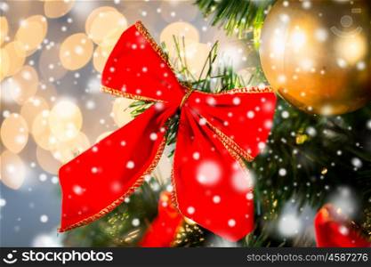 holidays, new year, decor and celebration concept - close up of christmas tree decorated with red bow and ball