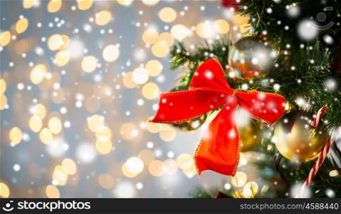 holidays, new year, decor and celebration concept - close up of christmas tree decorated with red bow and balls