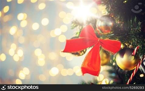 holidays, new year, decor and celebration concept - close up of christmas tree decorated with red bow and balls. close up of red bow decoration on christmas tree