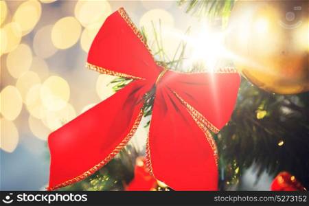 holidays, new year, decor and celebration concept - close up of christmas tree decorated with red bow and ball. close up of red bow decoration on christmas tree