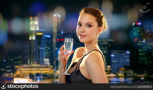 holidays, nightlife, drinks, people and luxury concept - beautiful young asian smiling woman drinking champagne at party over singapore city night lights background