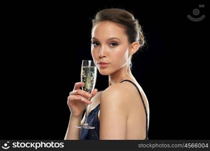 holidays, nightlife, drinks, people and luxury concept - beautiful young asian woman drinking champagne at party over black background and spotlights
