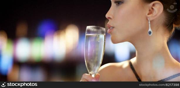 holidays, nightlife, drinks, people and luxury concept - close up of beautiful young asian woman drinking champagne at party over night lights background