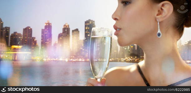 holidays, nightlife, drinks, people and luxury concept - close up of beautiful young asian woman drinking champagne at party over dubai city night lights background