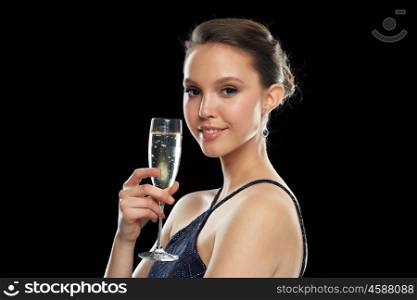holidays, nightlife, drinks, people and luxury concept - smiling beautiful young asian woman drinking champagne at party over black background and spotlights