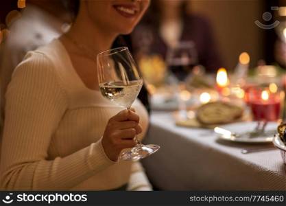 holidays, party and celebration concept - close up of happy smiling woman having christmas dinner at home and drinking white wine. close up of woman drinking wine at christmas party