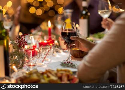 holidays, party and celebration concept - close up of man having christmas dinner at home and drinking red wine. close up of man drinking wine at christmas party