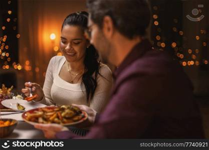 holidays, party and celebration concept - happy friends having christmas dinner at home. happy friends having christmas dinner at home