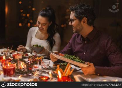 holidays, party and celebration concept - happy friends having christmas dinner at home. happy friends having christmas dinner at home