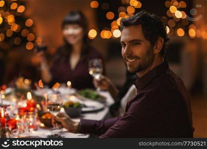 holidays, party and celebration concept - happy smiling man having christmas dinner with friends at home. happy man having christmas dinner with friends