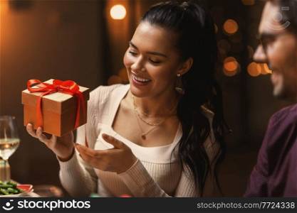holidays, party and celebration concept - happy smiling woman with gift box on christmas dinner at home. happy smiling woman with christmas gift at home