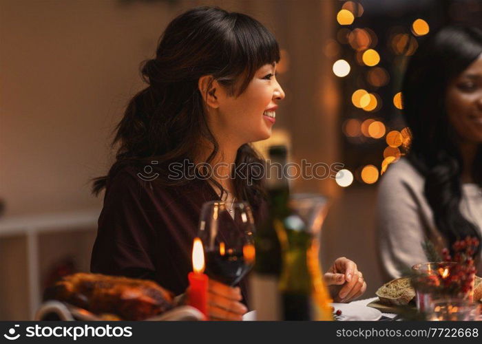 holidays, party and celebration concept - multiethnic group of happy friends having christmas dinner at home and drinking wine. happy friends drinking wine at christmas party