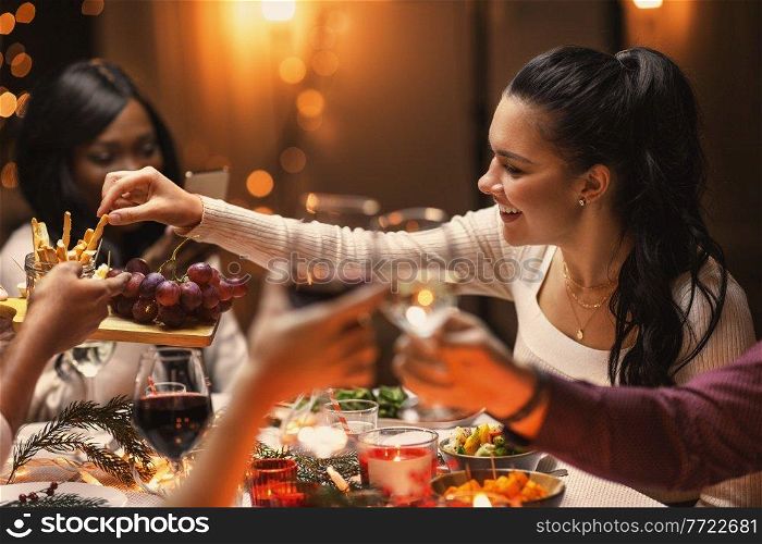 holidays, party and celebration concept - multiethnic group of happy friends having christmas dinner and sharing food at home. happy friends having christmas dinner at home