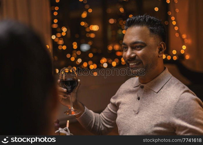 holidays, party and celebration concept - multiethnic group of happy friends having christmas dinner at home and drinking wine. happy friends drinking wine at christmas party