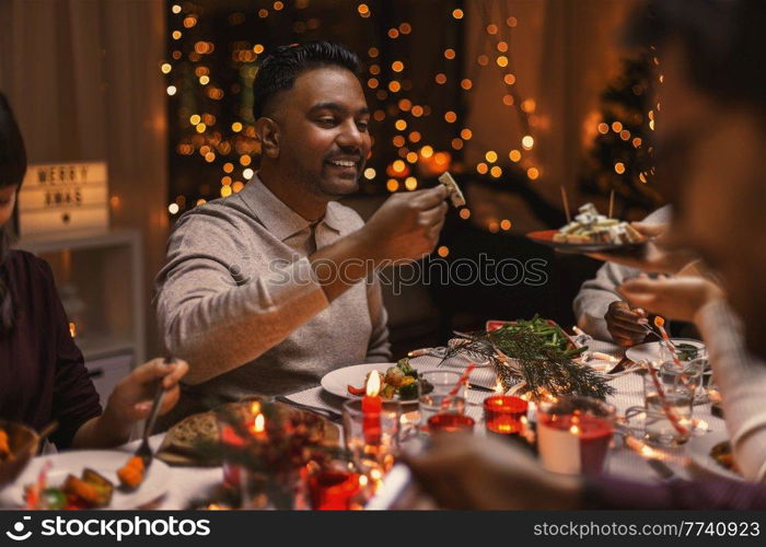 holidays, party and celebration concept - multiethnic group of happy friends having christmas dinner at home. happy friends having christmas dinner at home