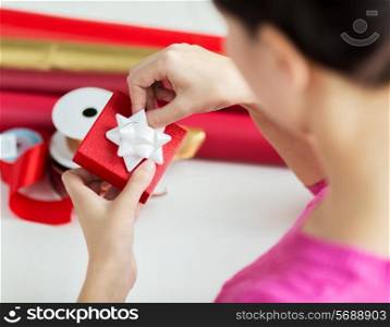 holidays, people and celebration concept - close up of woman decorating christmas present