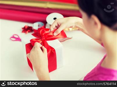holidays, people and celebration concept - close up of woman decorating christmas present