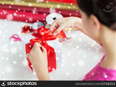 holidays, people and celebration concept - close up of woman decorating christmas present at home