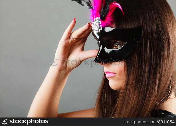Holidays, people and celebration concept. Closeup woman face profile with carnival venetian mask on gray background.