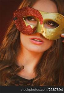 Holidays, people and celebration concept. Closeup woman face with carnival golden red mask on dark background.. Closeup woman face with carnival golden red mask on dark