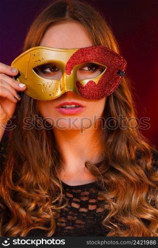 Holidays, people and celebration concept. Closeup woman face with carnival golden red mask on dark background.. Closeup woman face with carnival golden red mask on dark