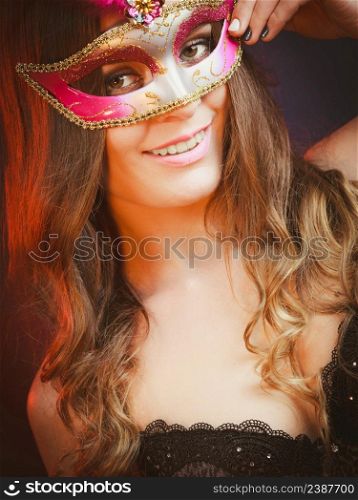 Holidays, people and celebration concept. Closeup woman face with carnival pink feather mask on dark background.. Closeup woman face with carnival mask on dark
