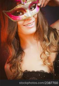 Holidays, people and celebration concept. Closeup woman face with carnival pink feather mask on dark background.. Closeup woman face with carnival mask on dark