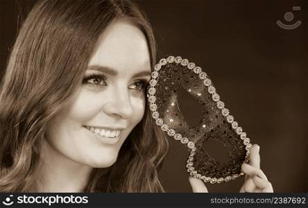 Holidays, people and celebration concept. Closeup woman face with carnival venetian mask on dark background, black and white photo. Closeup woman face with carnival mask on dark