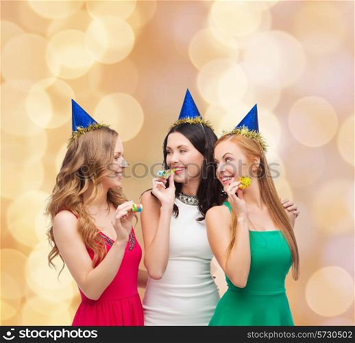 holidays, people and celebration concept - smiling women in party caps blowing to whistles over beige lights background