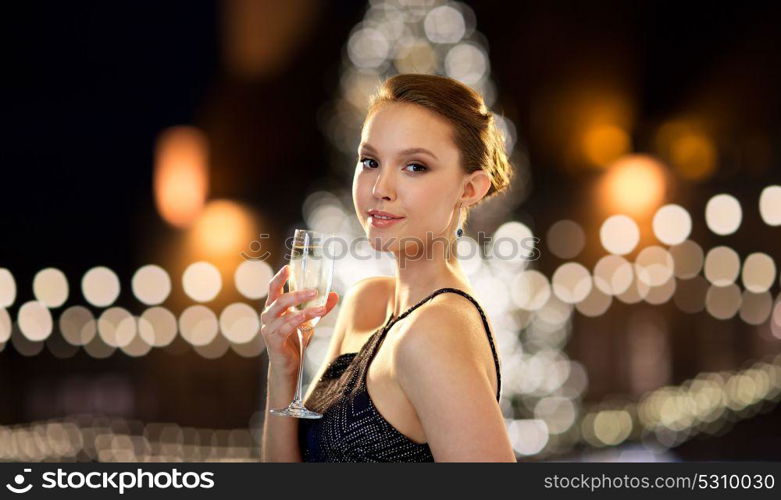 holidays, people and luxury concept - beautiful young asian smiling woman drinking non alcoholic champagne at party over christmas tree lights background. young asian woman drinking champagne at christmas