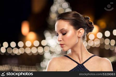 holidays, people and luxury concept - beautiful young asian woman over christmas tree lights background. beautiful asian woman over christmas tree lights