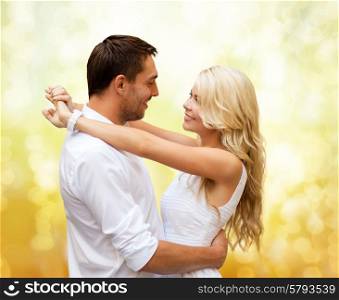 holidays, people, love and dating concept - happy couple hugging over yellow lights background