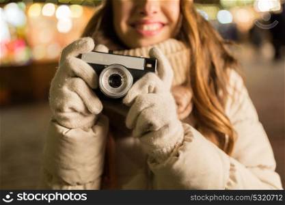 holidays, photography and people concept - close up of happy young woman with camera at christmas market in winter evening. close up of happy woman with camera at christmas