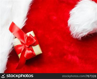 Holidays, present, christmas concept. Small golden box with gift tied decorative bow on red background