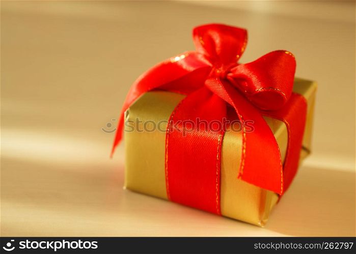 Holidays, present, christmas concept. Small golden box with gift tied decorative red bow