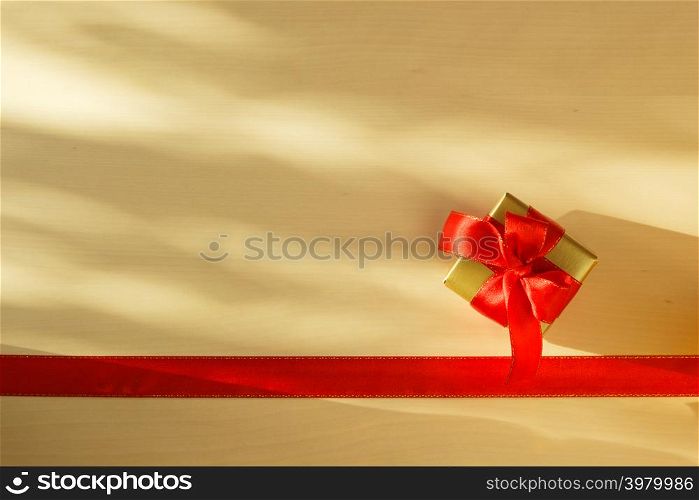 Holidays, present concept. Small golden box with gift tied decorative bow and red ribbon frame