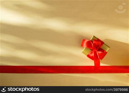Holidays, present concept. Small golden box with gift tied decorative bow and red ribbon frame