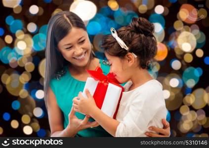holidays, presents and people concept - happy mother and child girl with gift box over lights background. happy mother and daughter girl with gift box
