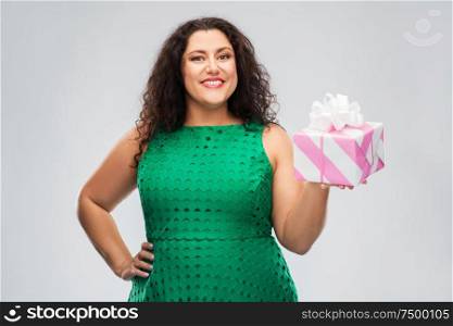holidays, presents and people concept - happy woman in green dress holding gift box over grey background. happy woman in green dress holding gift box