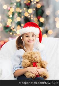 holidays, presents, childhood and people concept - smiling little girl with teddy bear toy over living room and christmas tree background