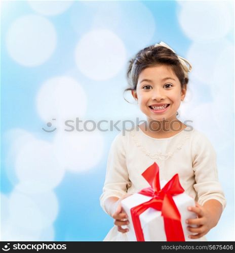 holidays, presents, christmas, childhood and people concept - smiling little girl girl with gift box over blue lights background