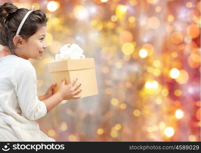 holidays, presents, christmas, childhood and people concept - smiling little girl with gift box over lights background