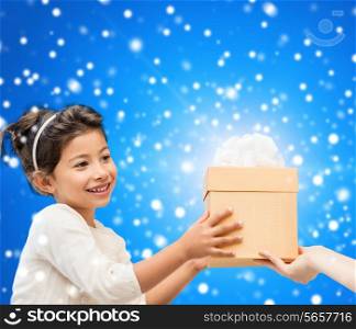 holidays, presents, christmas, childhood and people concept - smiling little girl with gift box over blue snowy background