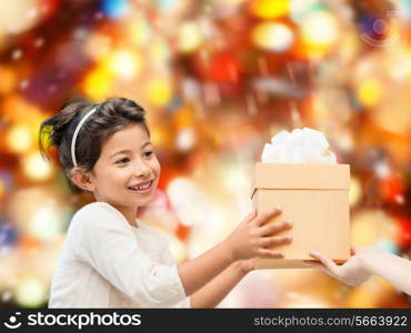 holidays, presents, christmas, childhood and people concept - smiling little girl with gift box over red lights background